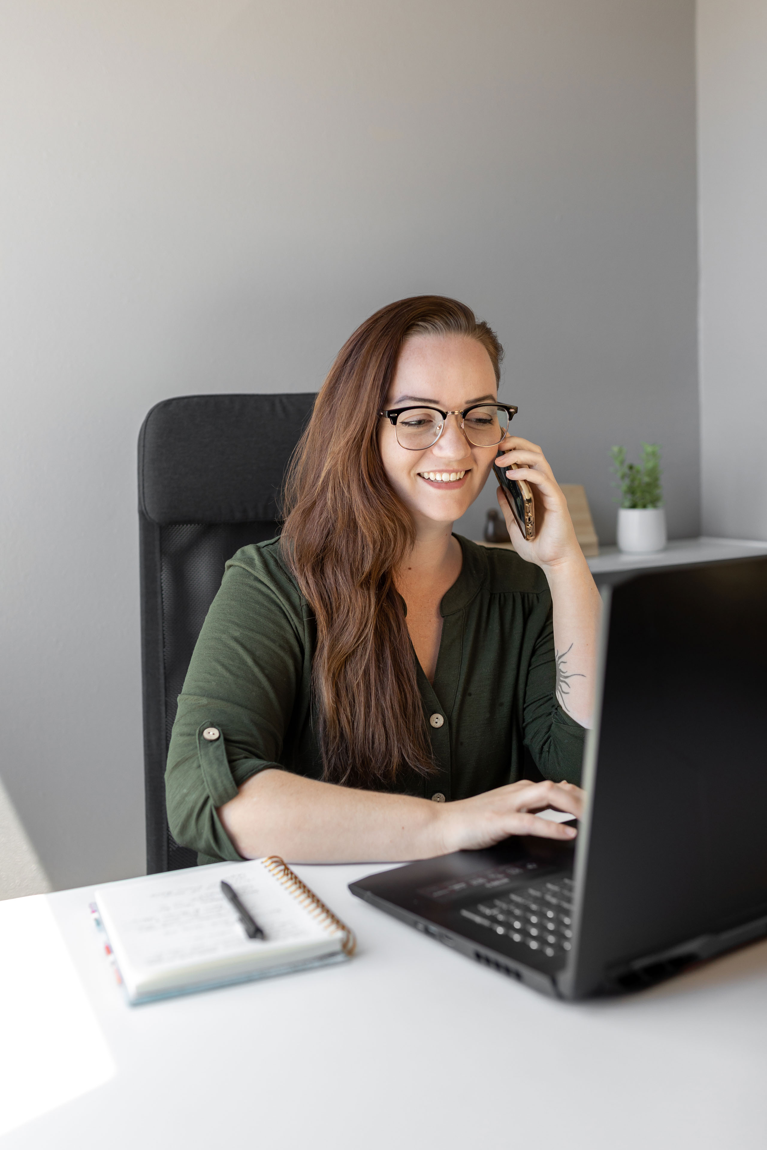 a woman sitting at a desk with a laptop while talking on the phone 1