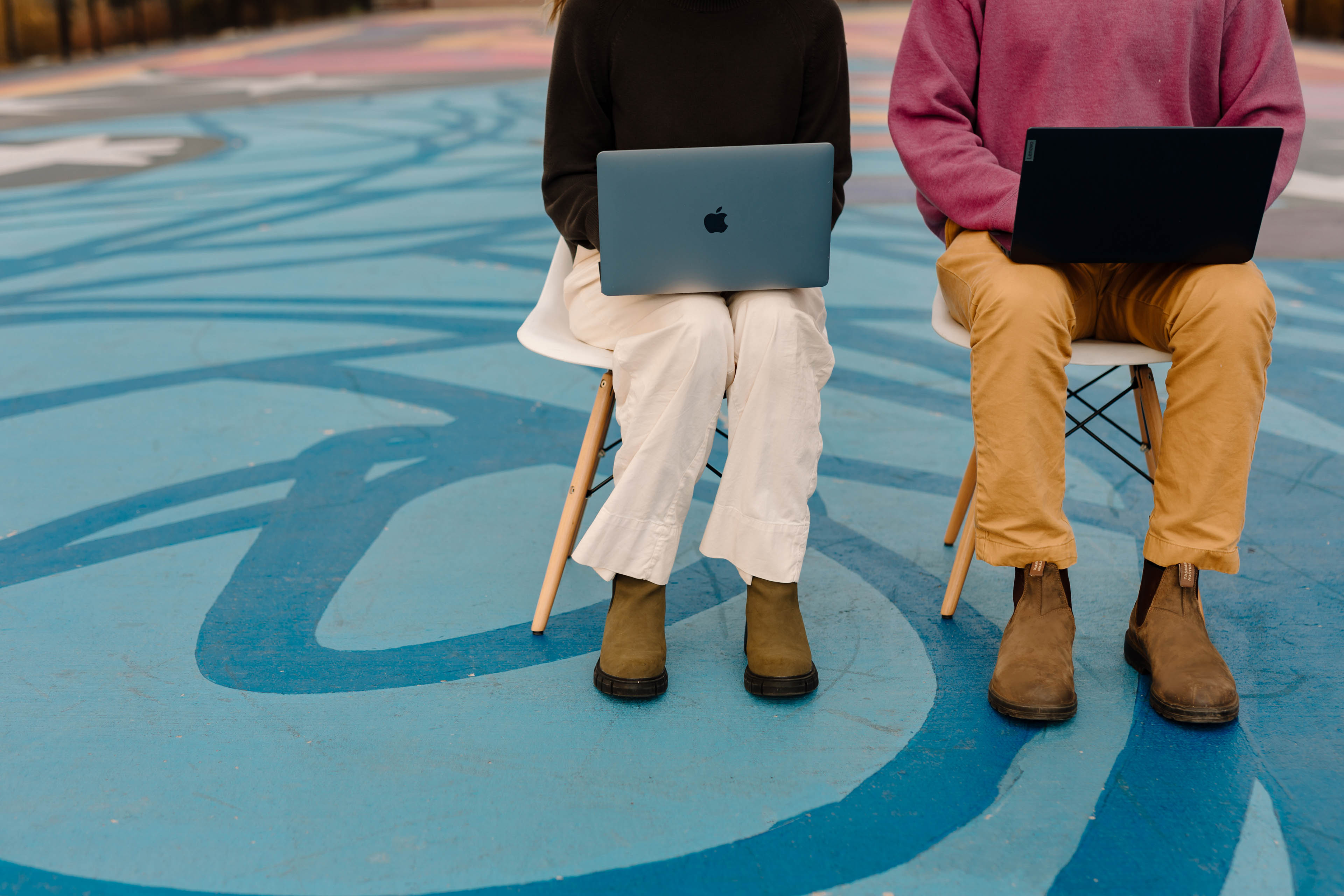 two people sitting in a colorful city with laptops