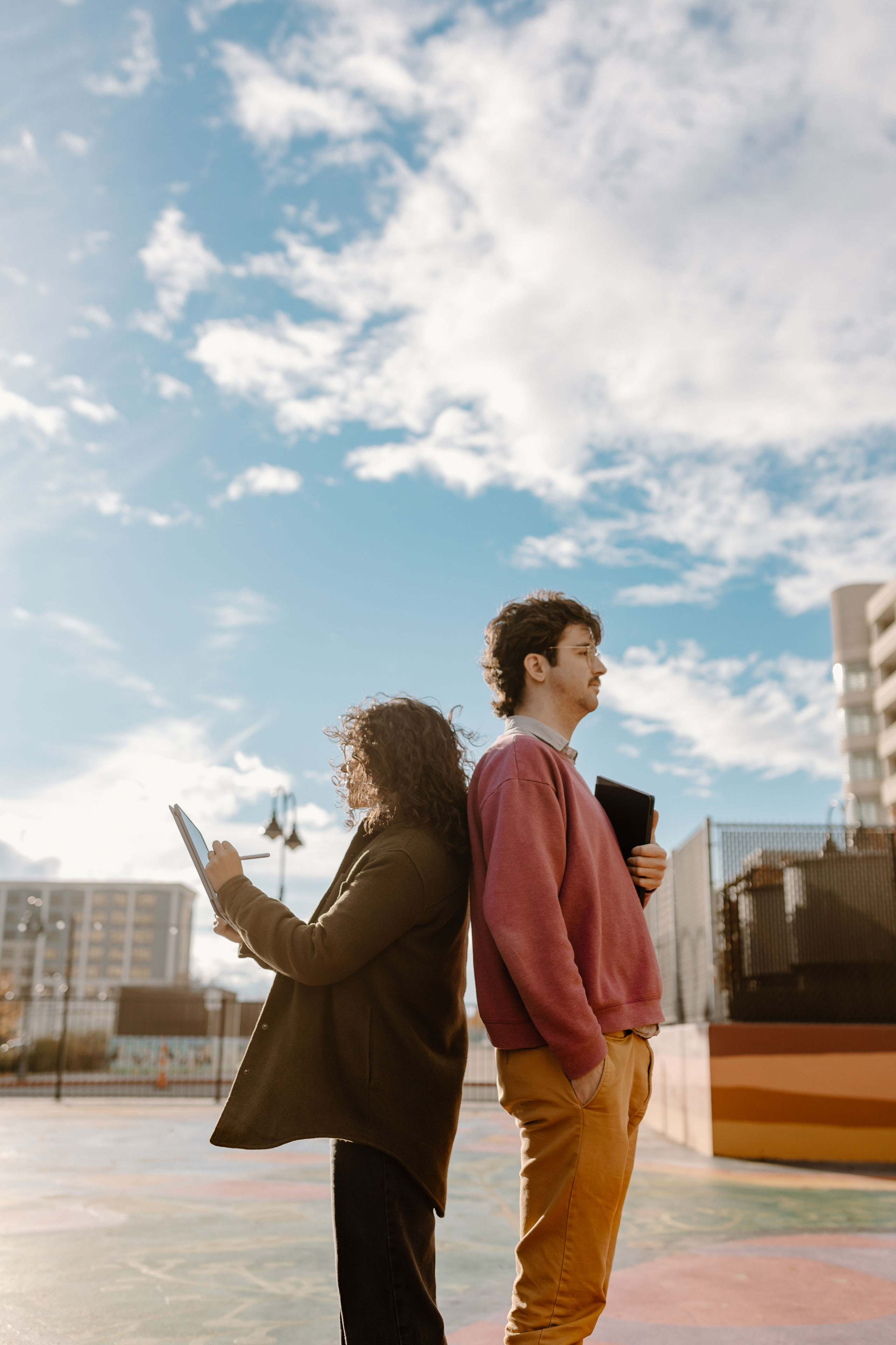 two people standing in a city holding ipads with blue skies in the background