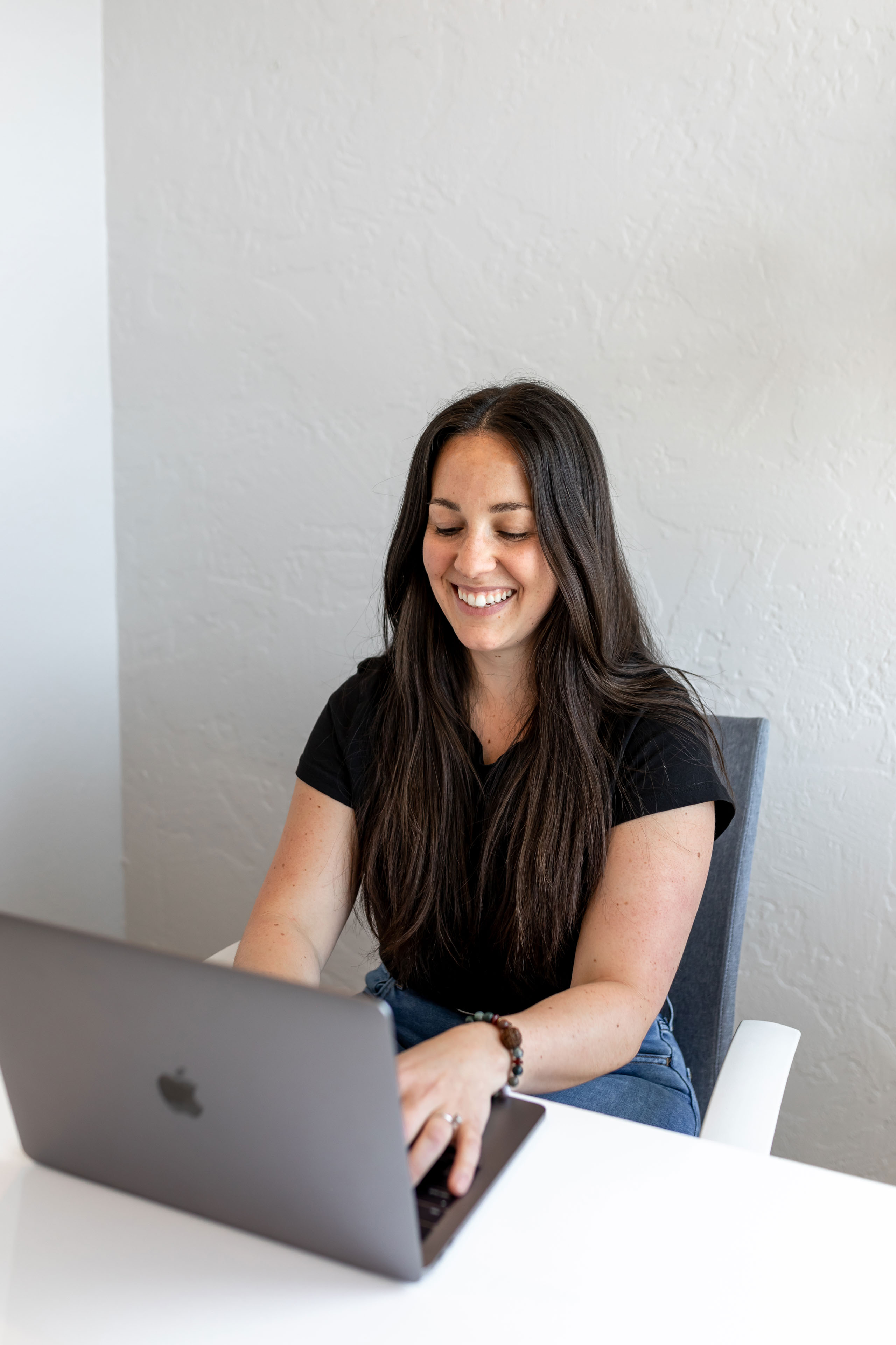 a woman typing on a laptop and smiling