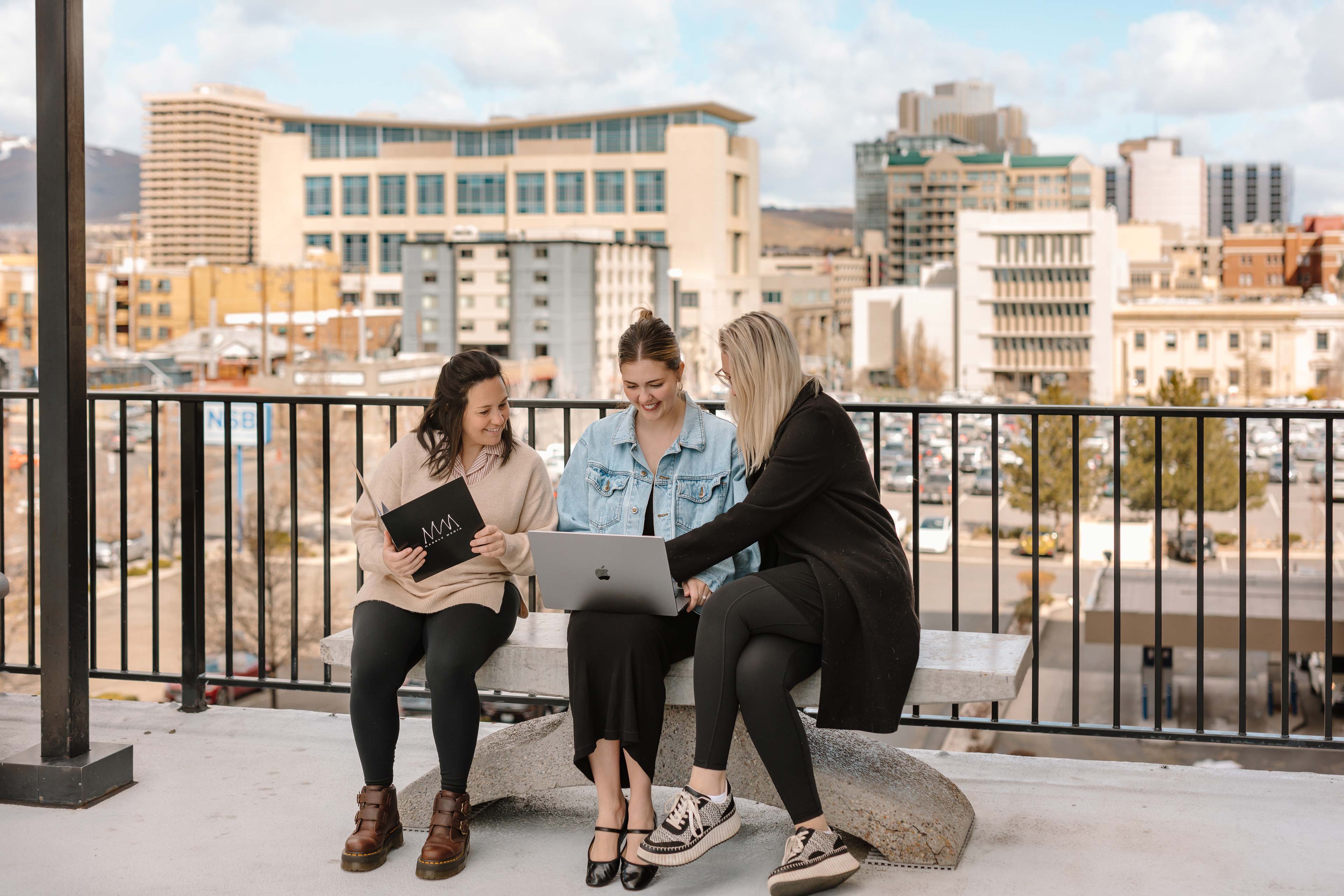 three people sitting on a bench in a city coworking