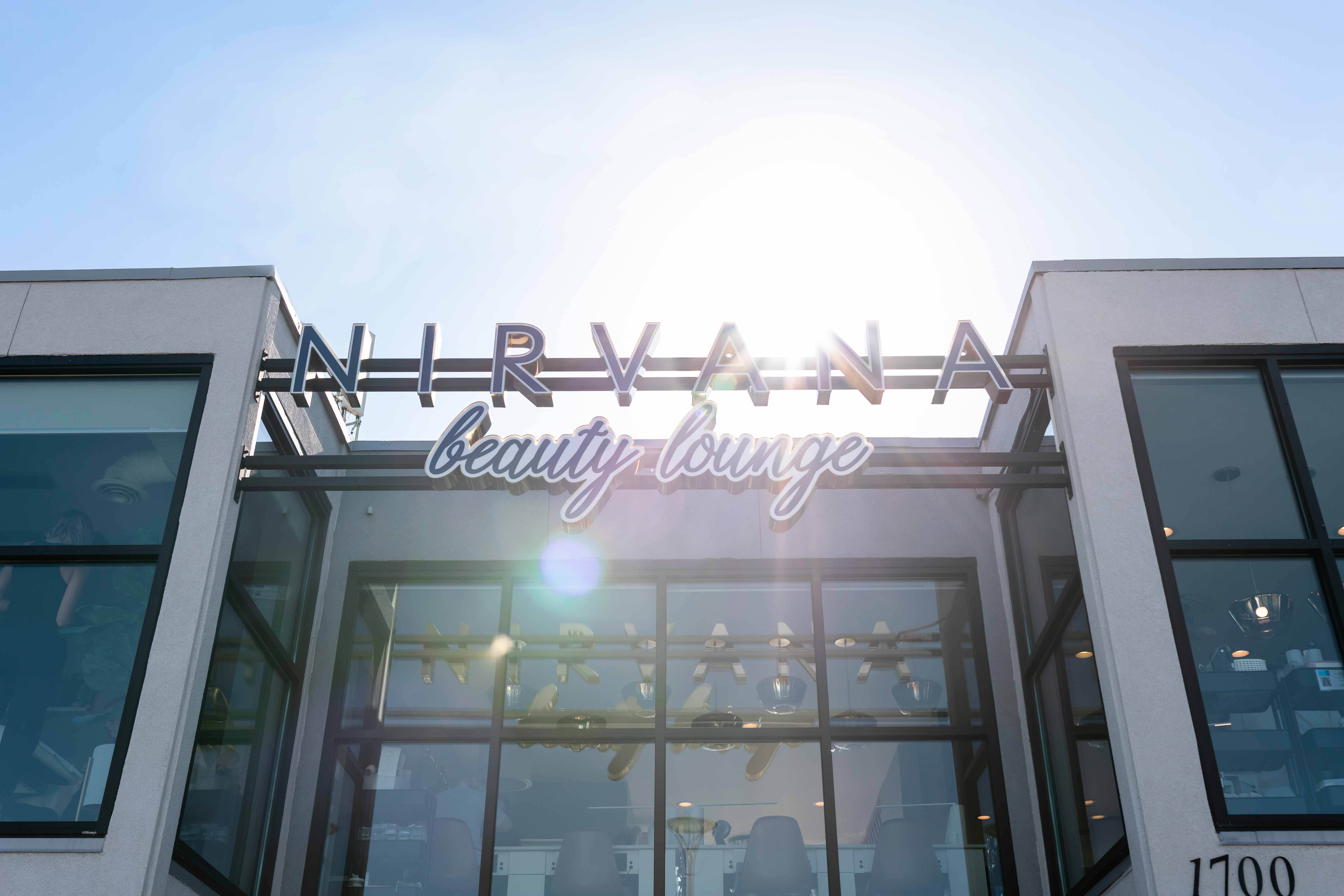 Building with lots of windows with bright blue sky behind it and sunlight peeking through the logo