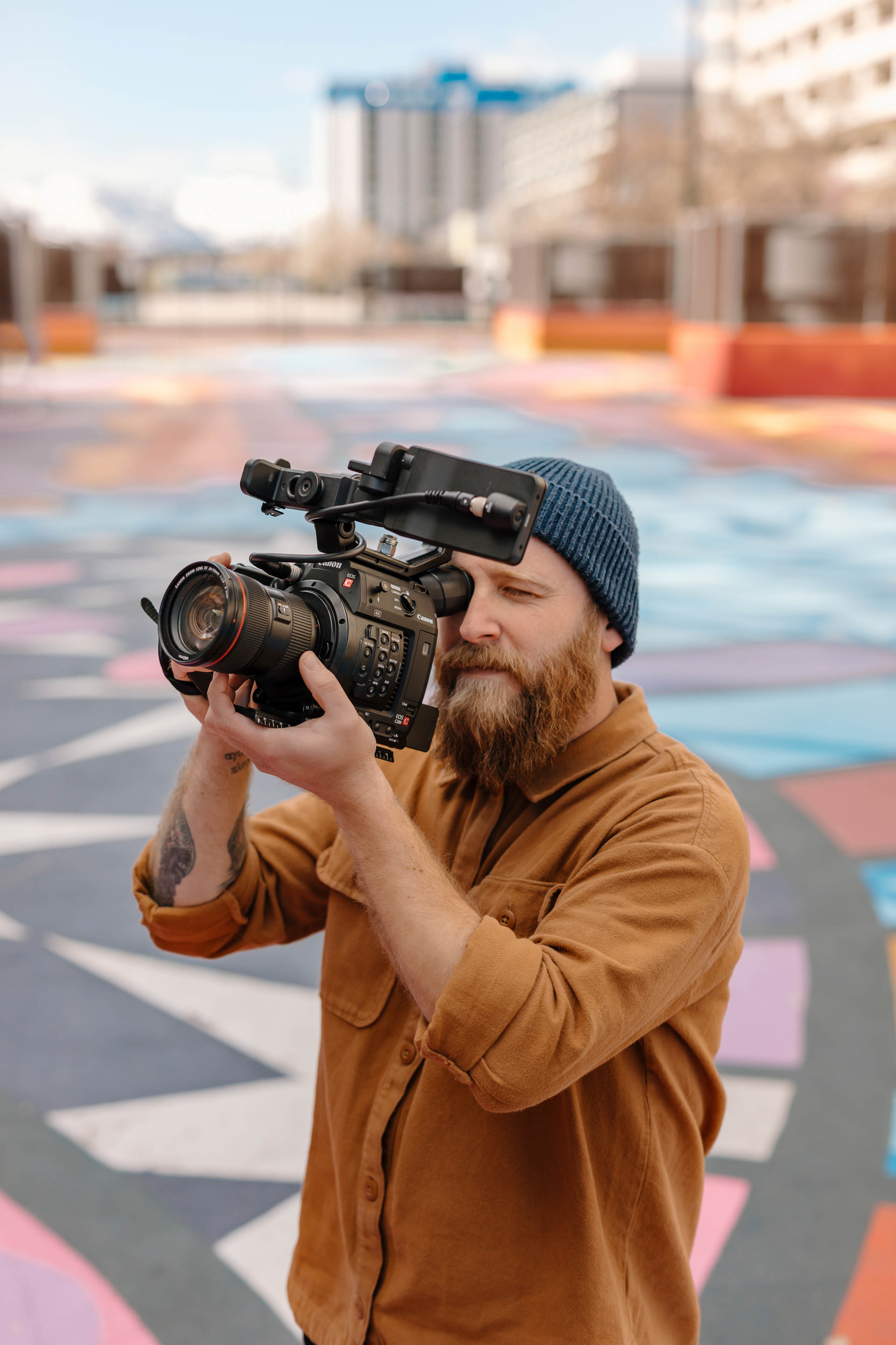 a videographer holding a camera in a colorful city