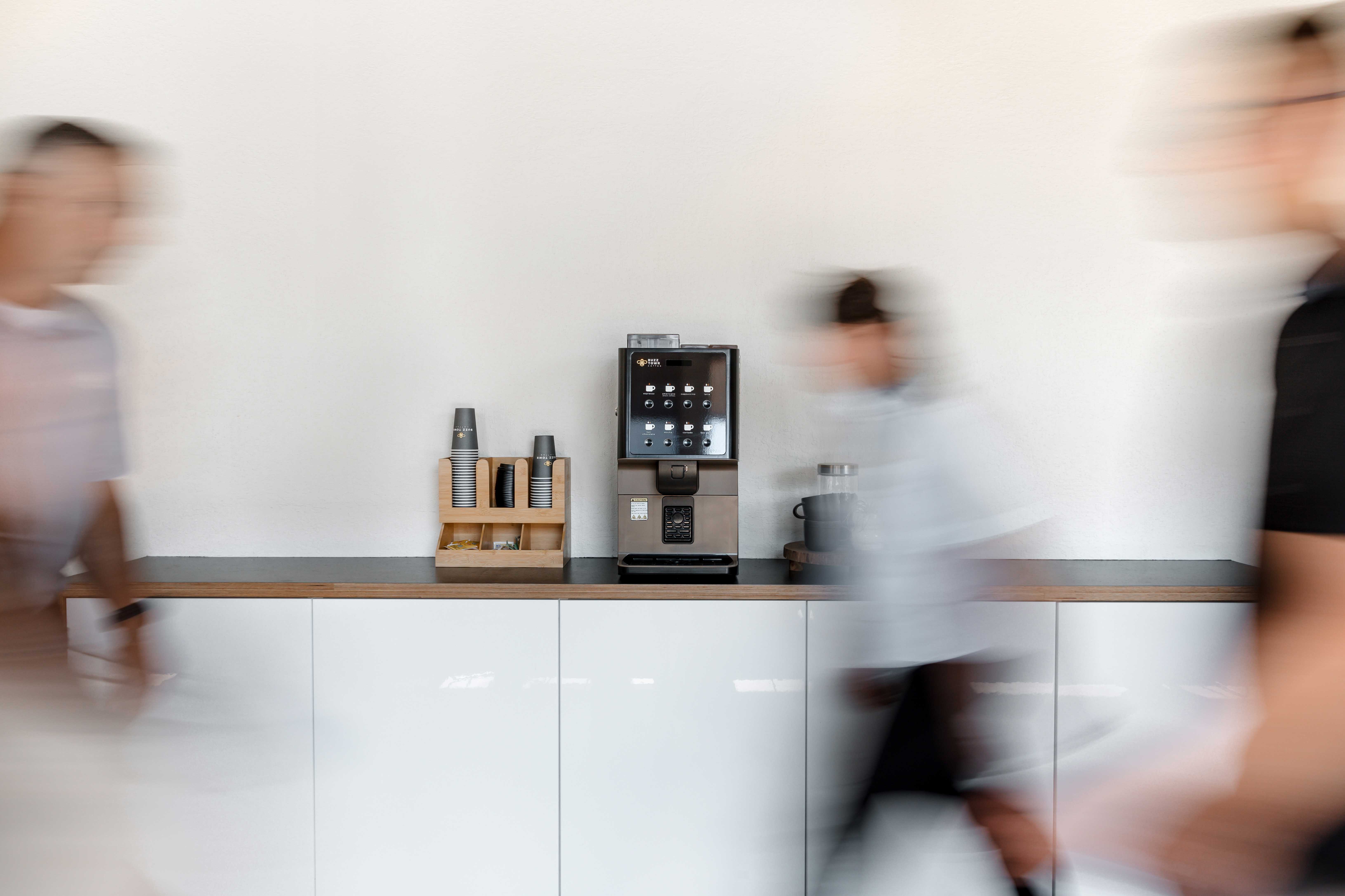 blurry people walking by with a coffee machine in the background