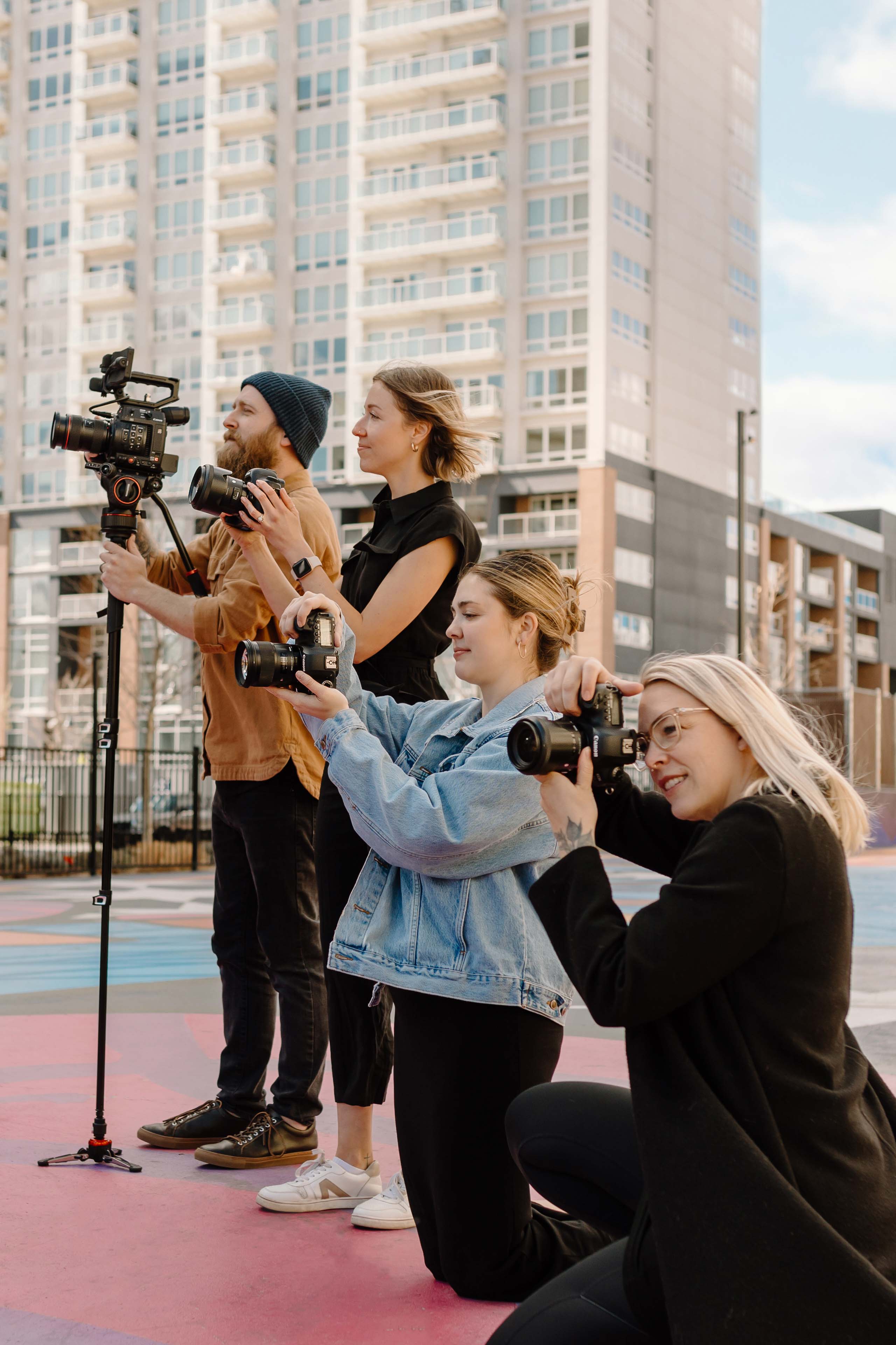 four people holding cameras in a city