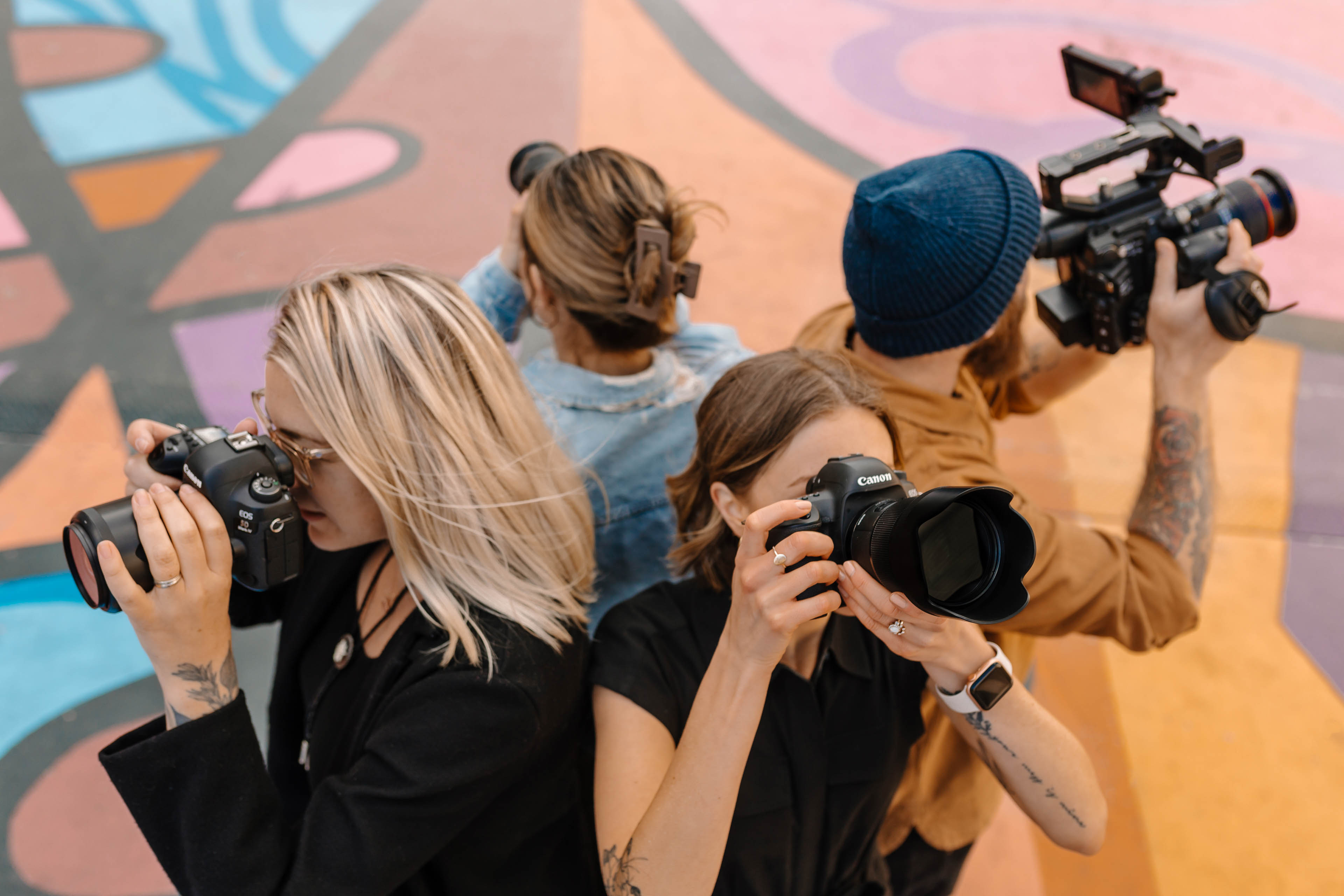 four people standing in a circle with cameras in a colorful city