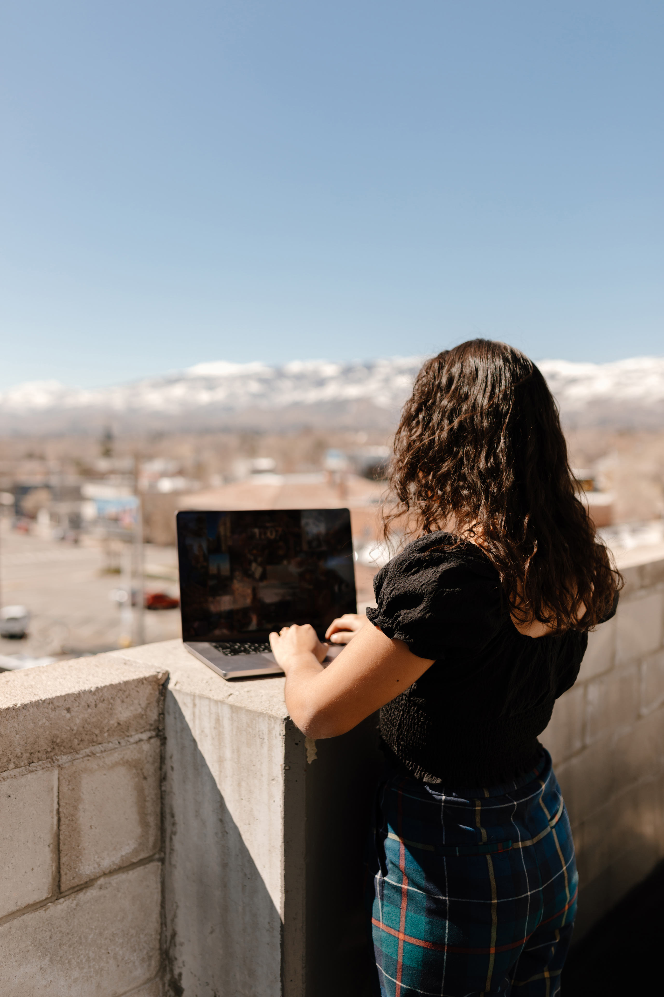 a woman standing in a city working on a laptop